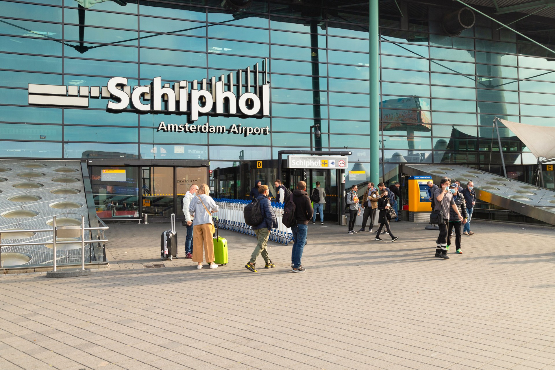 Travelers in front of the entrance to the central hall of Schiphol airport.